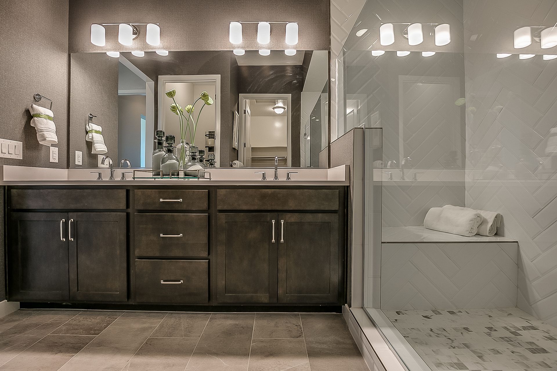 Modern bathroom with double vanity, mirror, and glass shower enclosure.