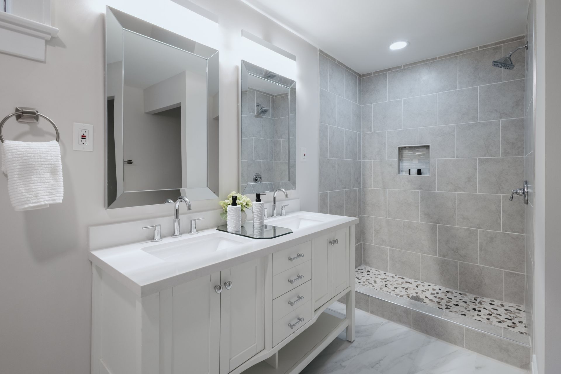 Modern bathroom remodel with double vanity and tiled walk-in shower with built-in niche.