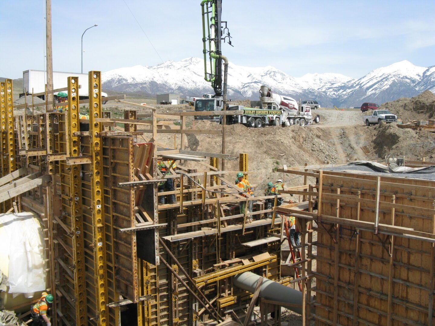 Construction site with concrete forms and machinery, mountains in the snowy background