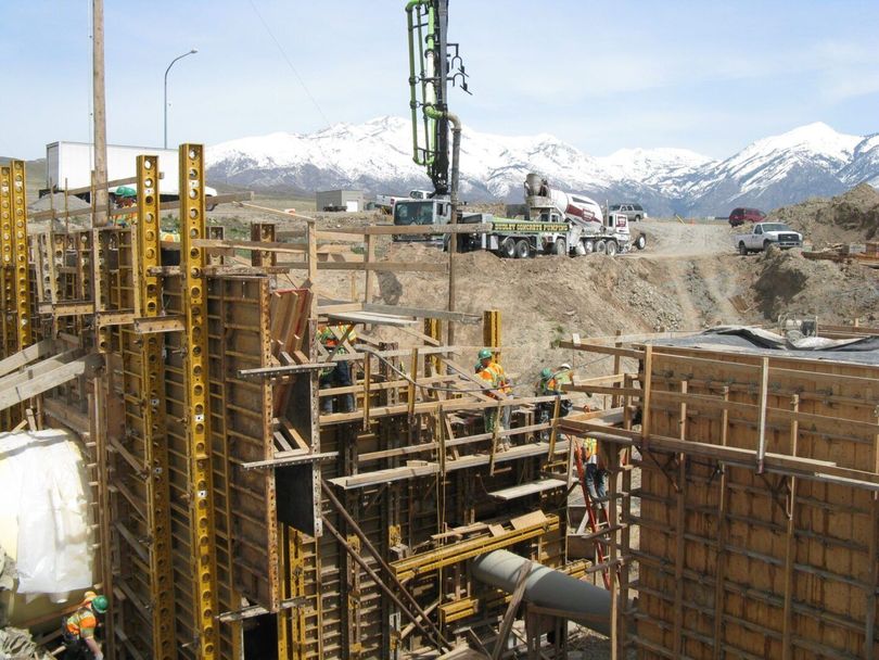 Construction site with concrete forms and machinery, mountains in the snowy background