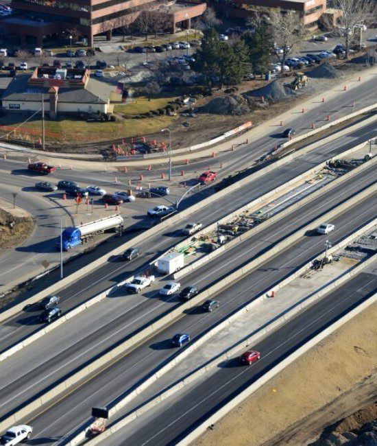 Aerial view of a busy multi-lane highway with cars and trucks near an interchange.
