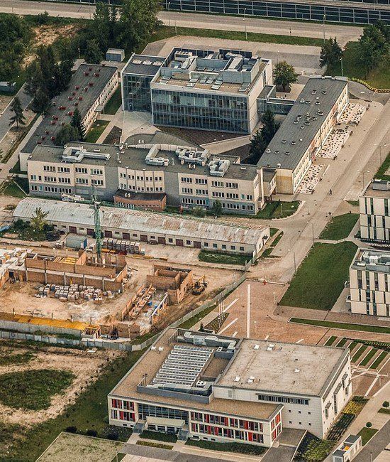 Aerial view of a modern campus with several buildings, roads, and a construction site.