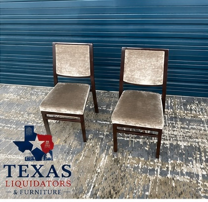 Two beige upholstered chairs on a worn blue floor in front of a blue garage door, Texas Liquidators logo visible
