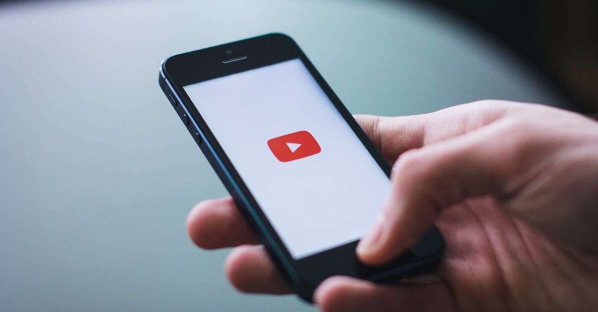 Hand holding a smartphone displaying the YouTube logo.