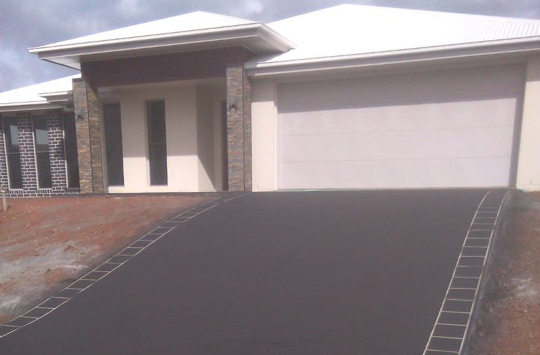 A sloped concrete driveway with decorative concreting.