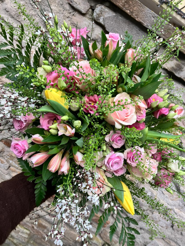Bouquet misto di fiori rosa e gialli con fogliame su una superficie rustica in mattoni