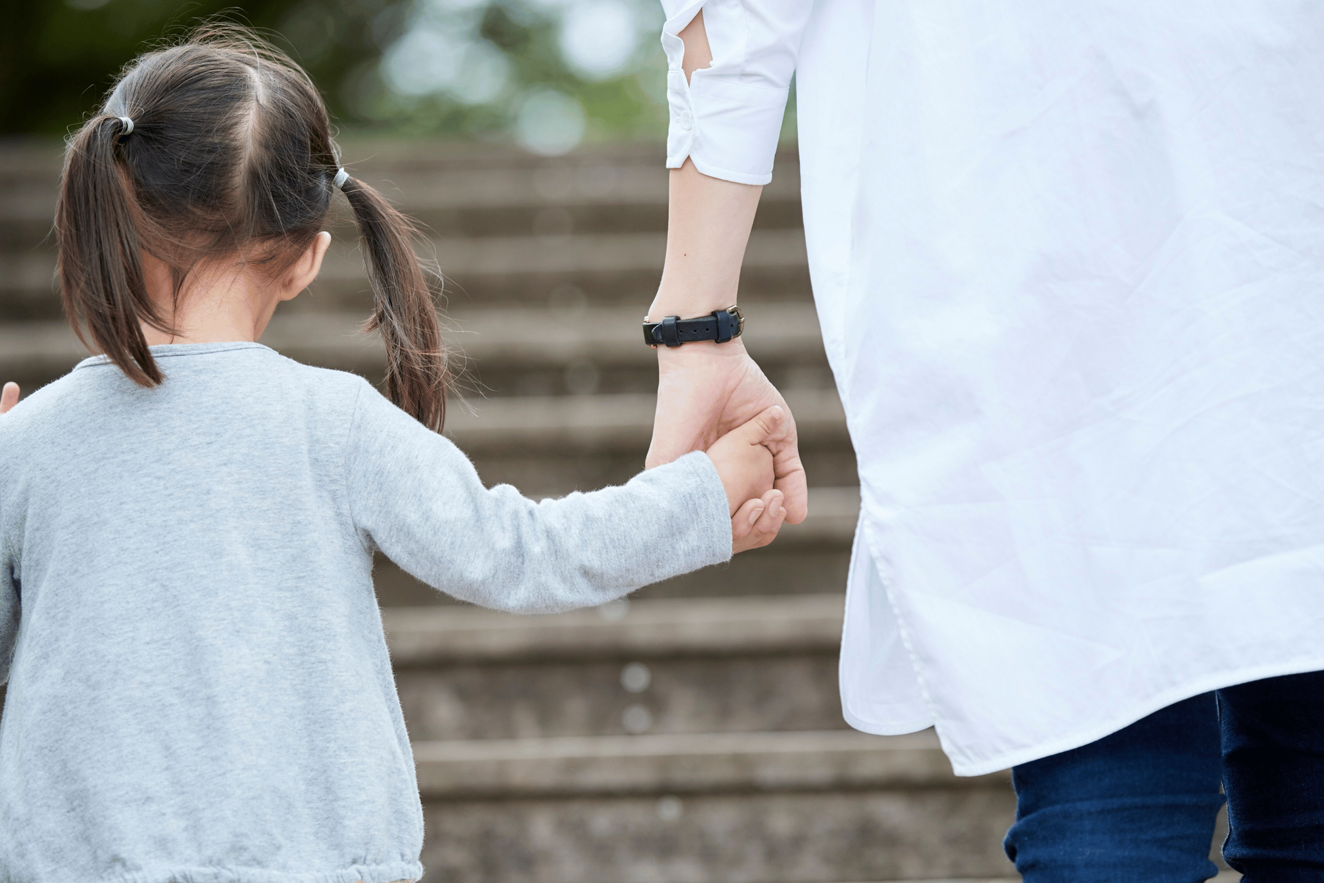 Adult and child holding hands while walking up outdoor steps