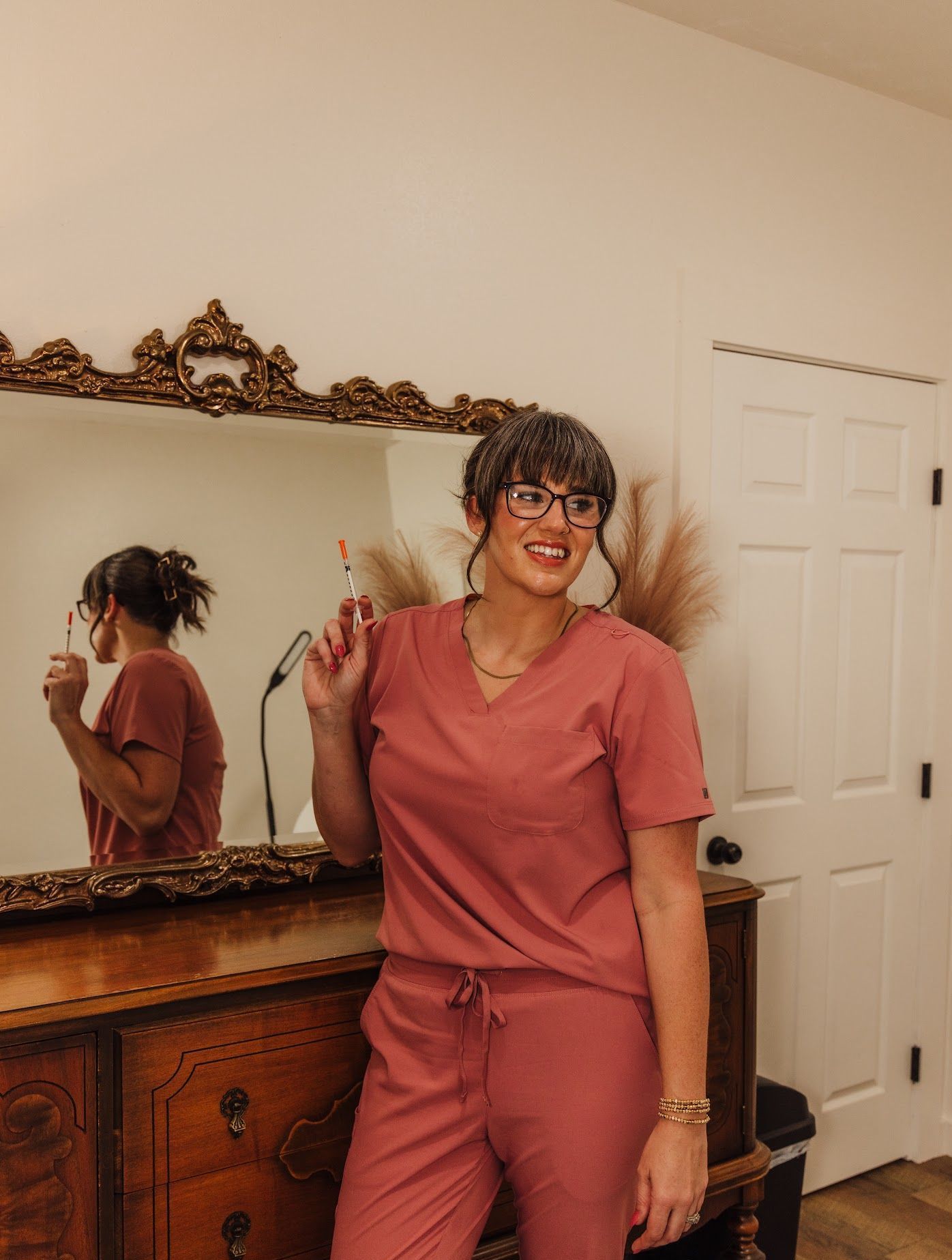 A woman in scrubs is standing in front of a mirror.
