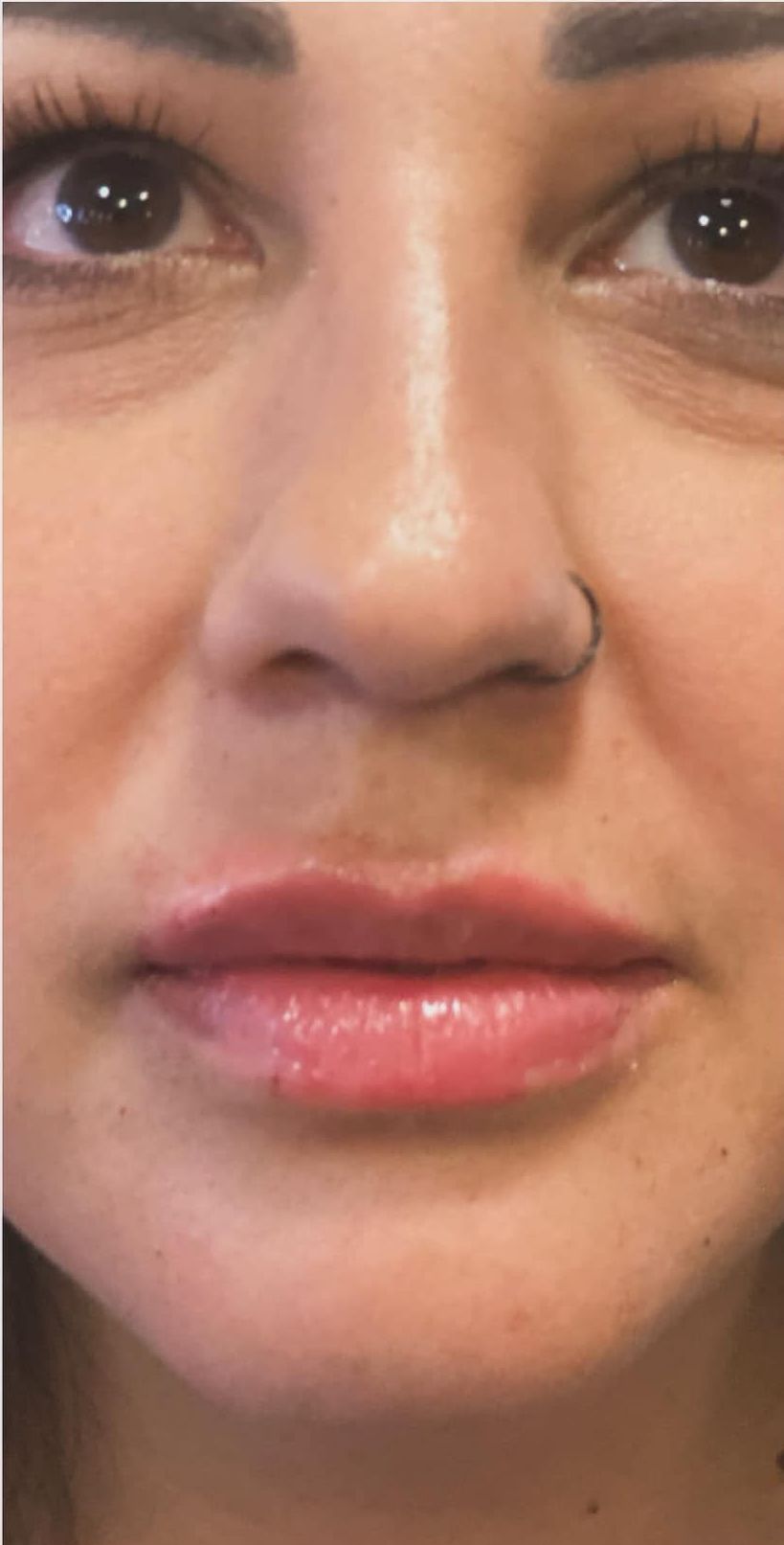 A close up of a woman 's face with a nose ring.