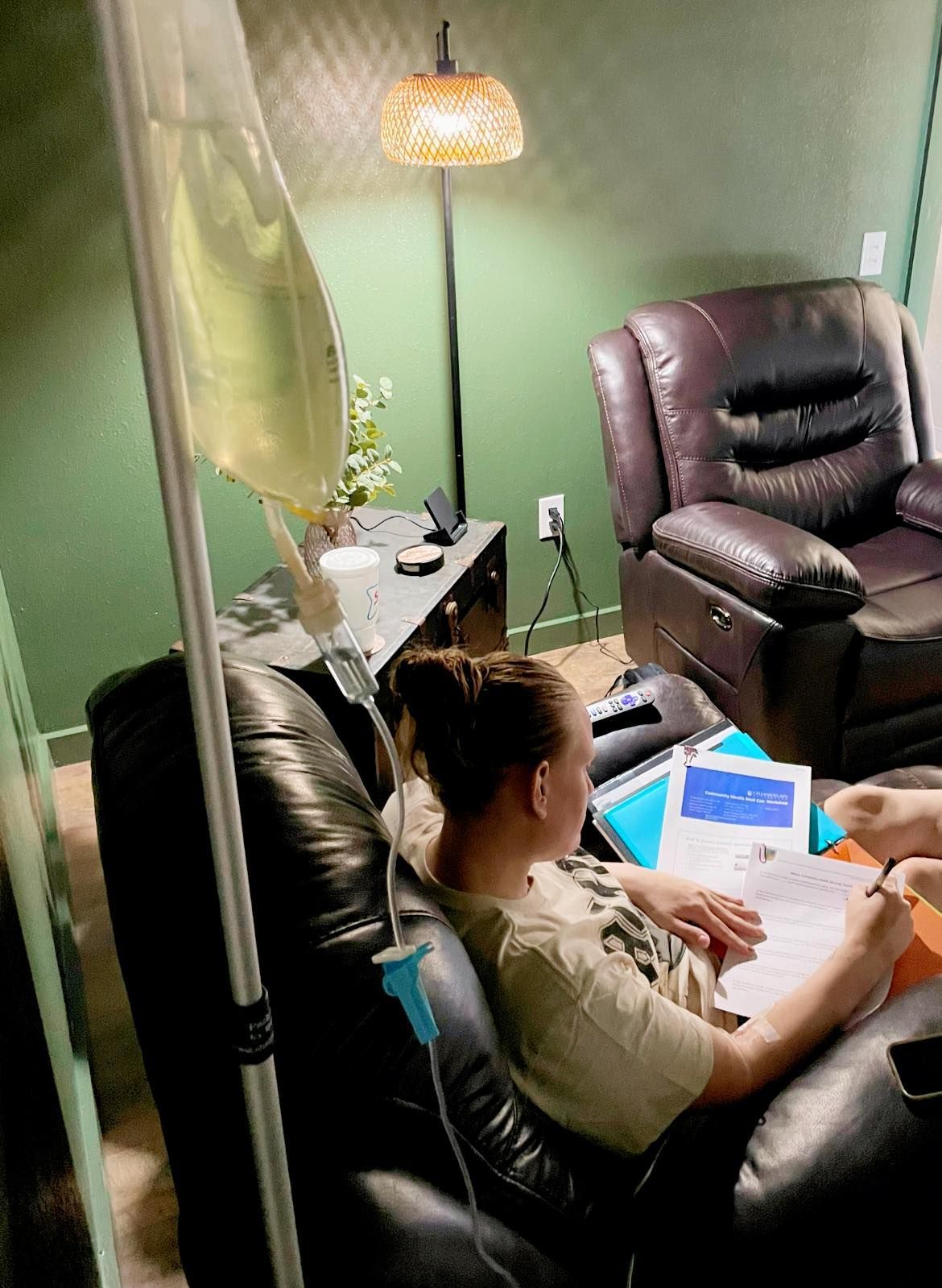A woman is sitting in a chair with an iv bag attached to her arm.