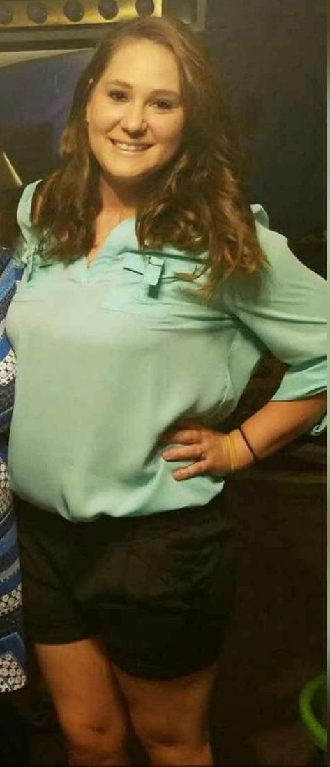 A woman in a blue shirt and black shorts is standing with her hands on her hips.