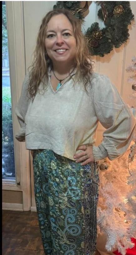 A woman is standing in front of a christmas tree with her hands on her hips.