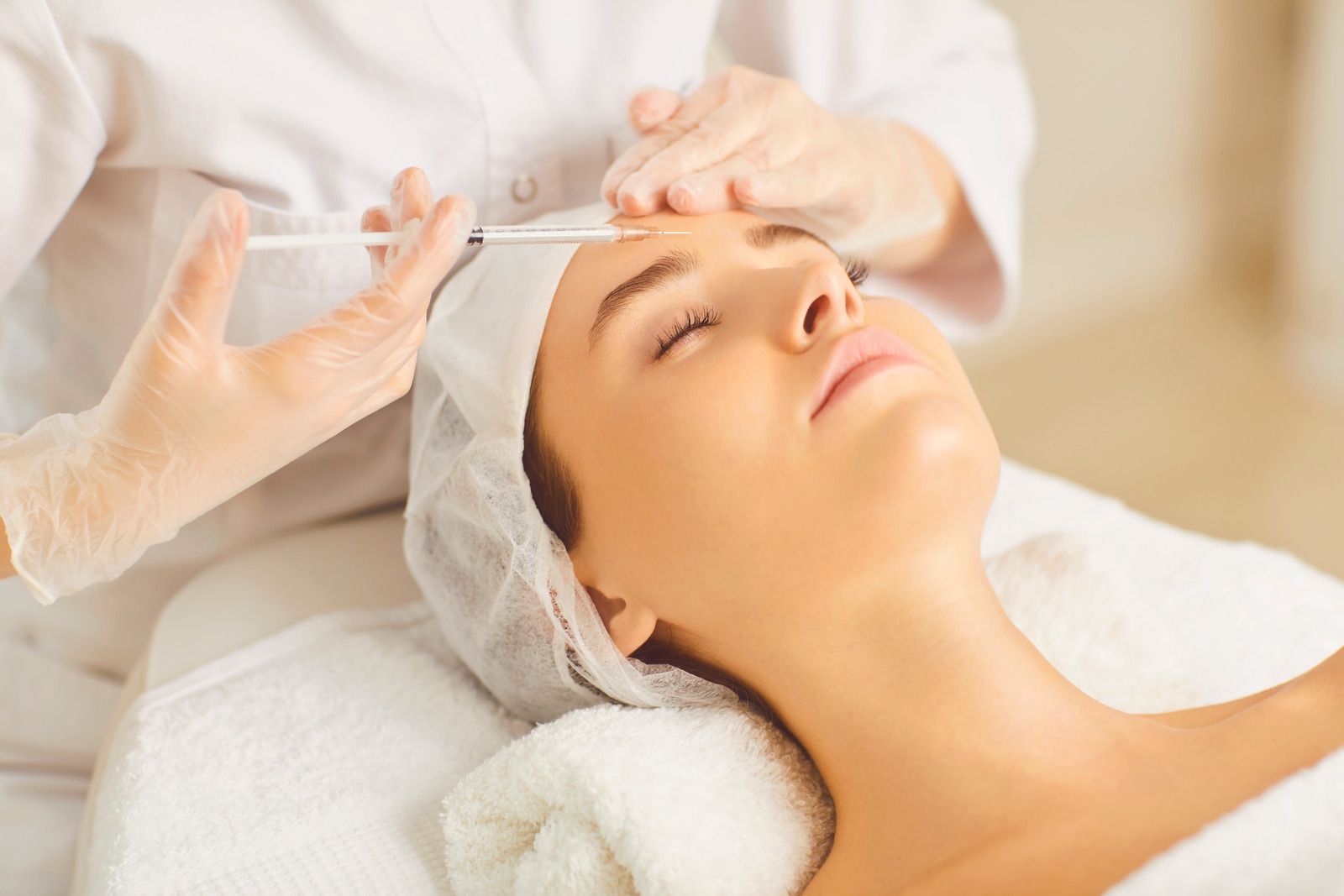 A woman is getting an injection in her forehead at a beauty salon.
