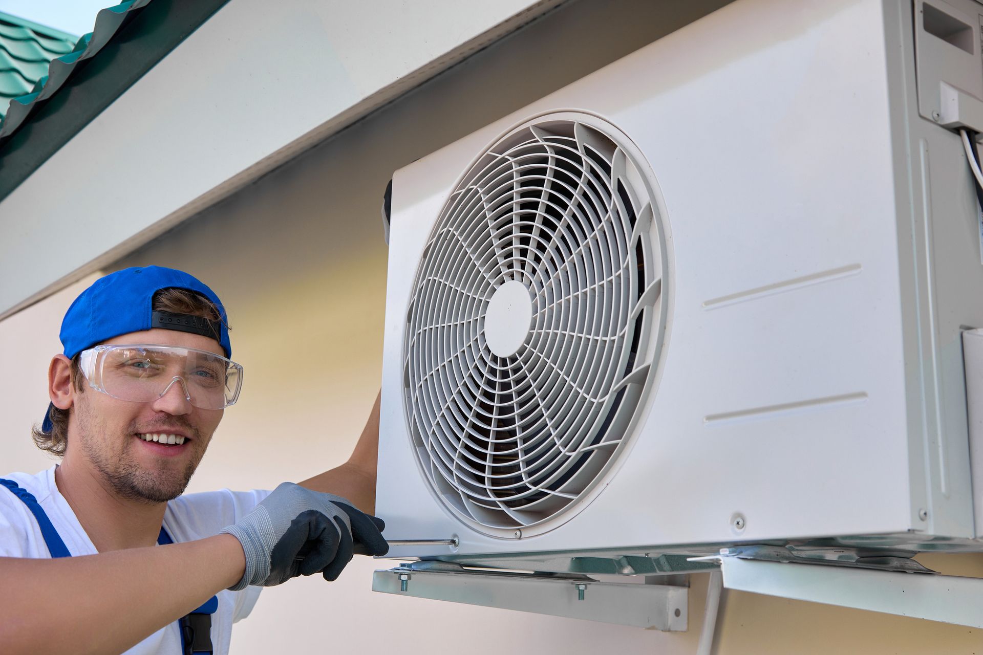 Split system installation by a smiling technician using a screwdriver.