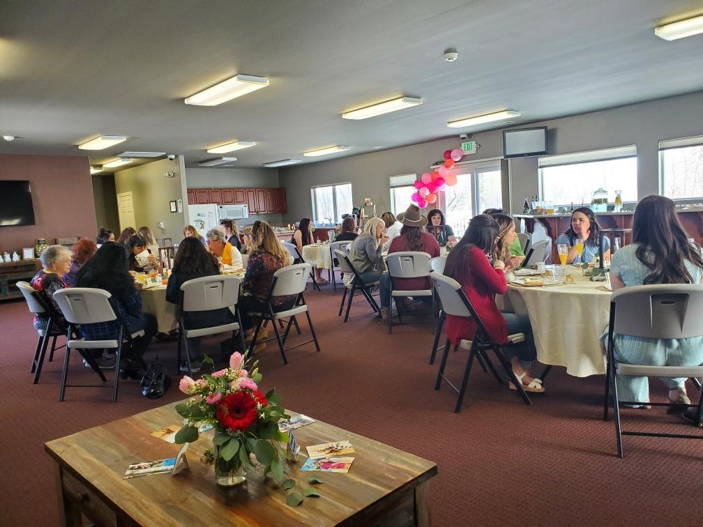 A group of people are sitting at tables in a large room.