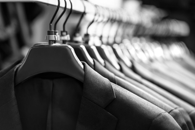 Row of black clothing jackets hanging on hangers in a store or closet