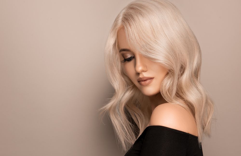 A Woman With Blonde Hair is Wearing a Black Top and Looking Down — Amore 'D' Hair Studio In Mudjimba, QLD