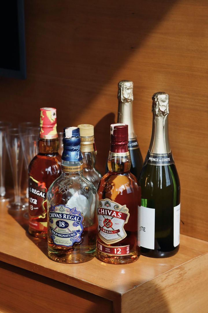 A collection of various liquor and champagne bottles arranged on a wooden surface.