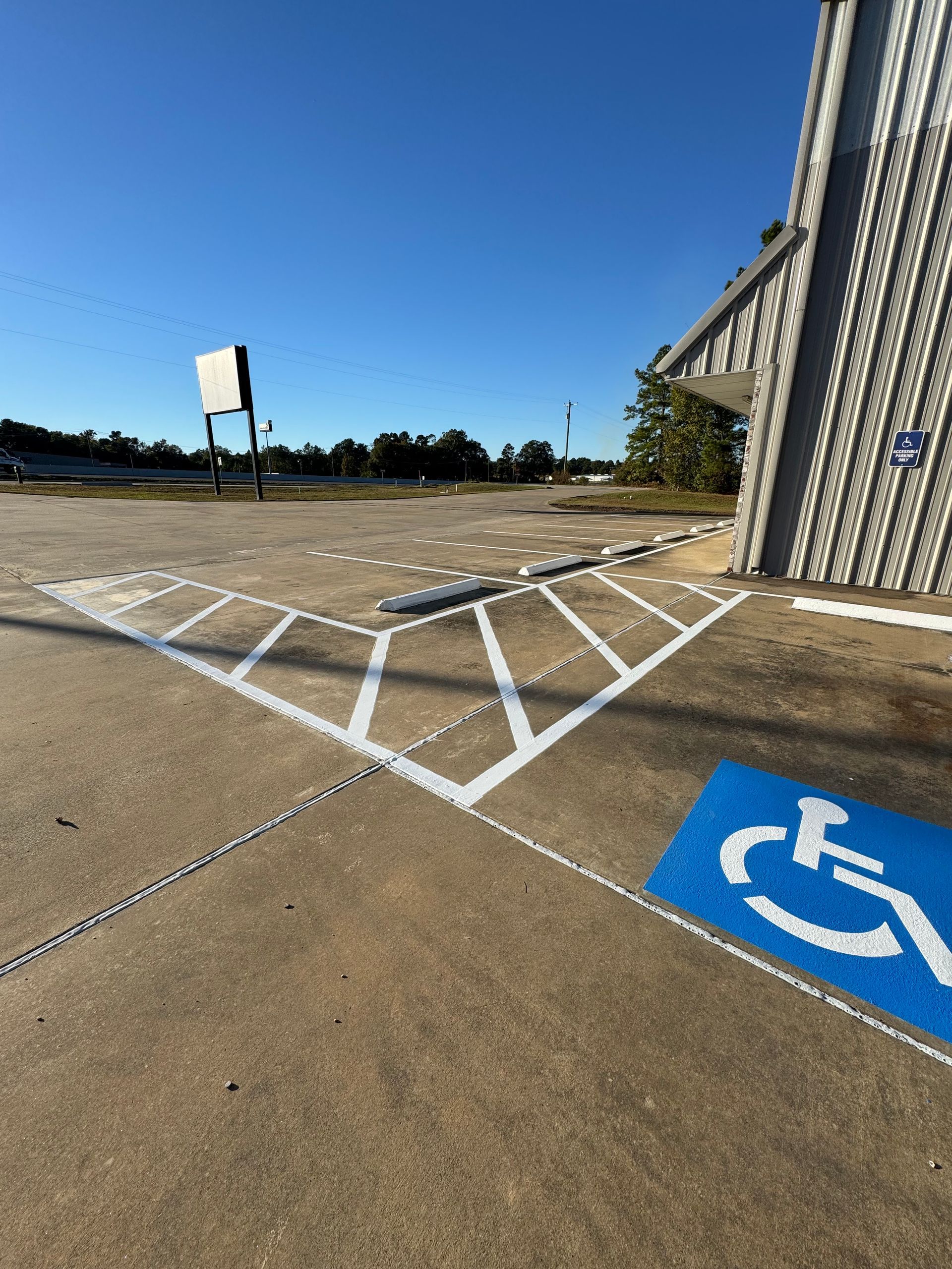 Accessible parking space with blue handicap symbol and white striped loading zone beside a building.