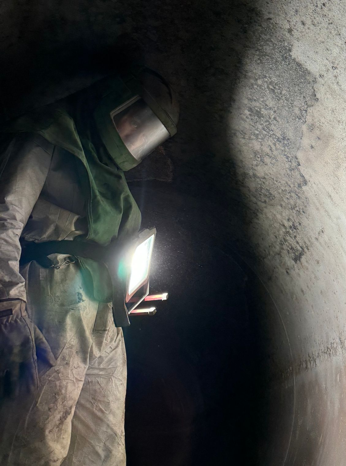Worker inside a tunnel using a bright flashlight and wearing protective gear