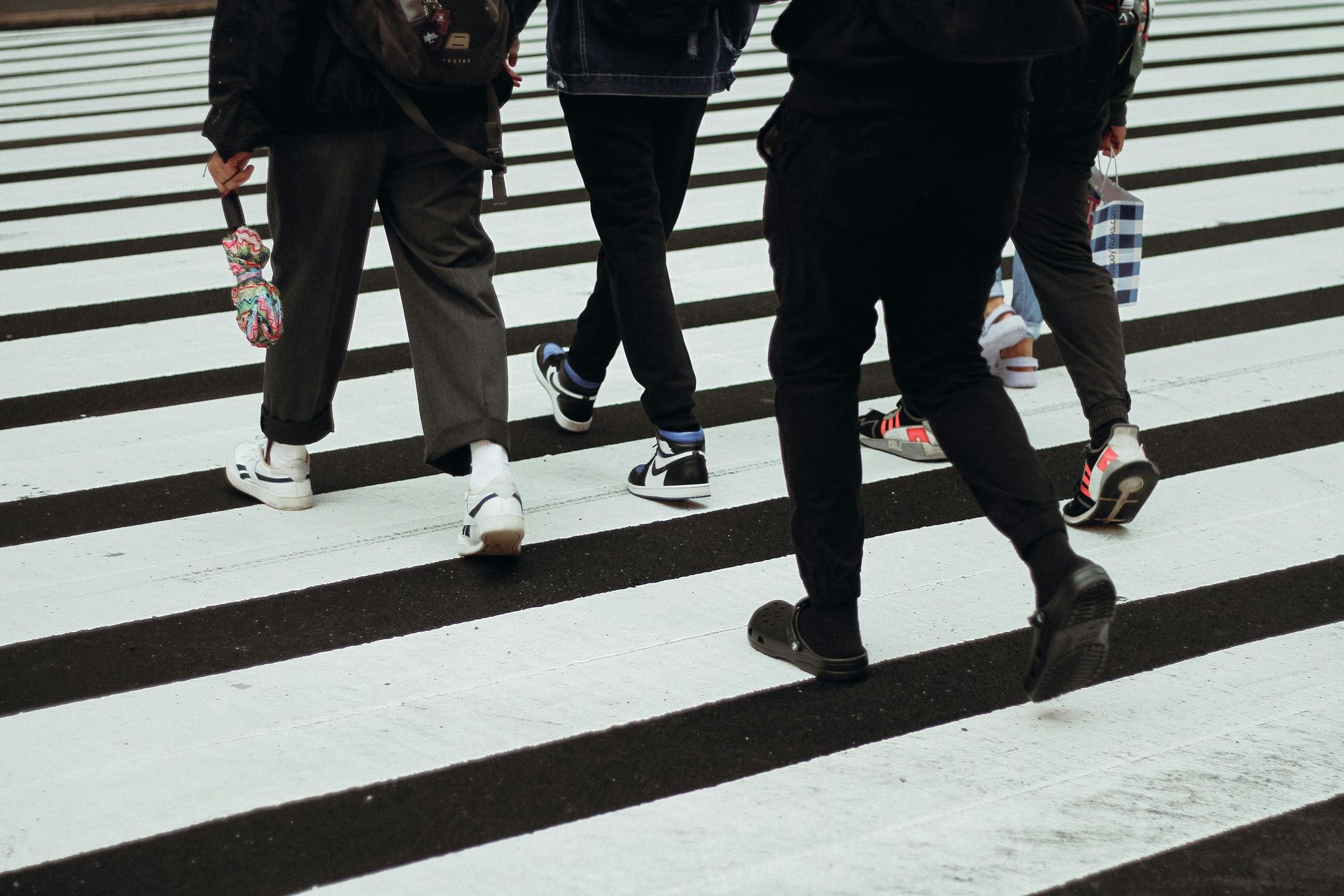 People walking across a black-and-white striped crosswalk