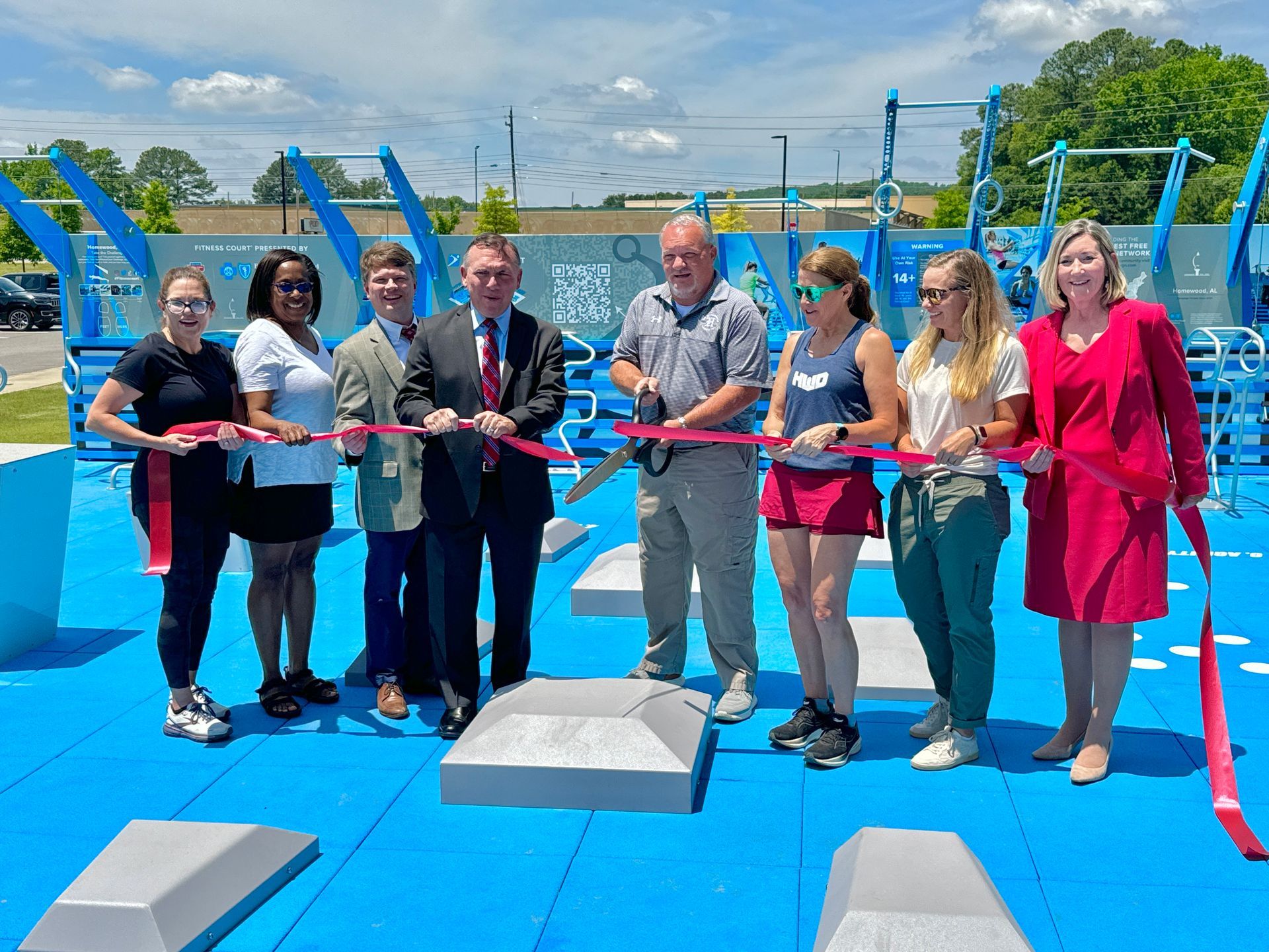 A group of people are standing next to each other cutting a red ribbon.