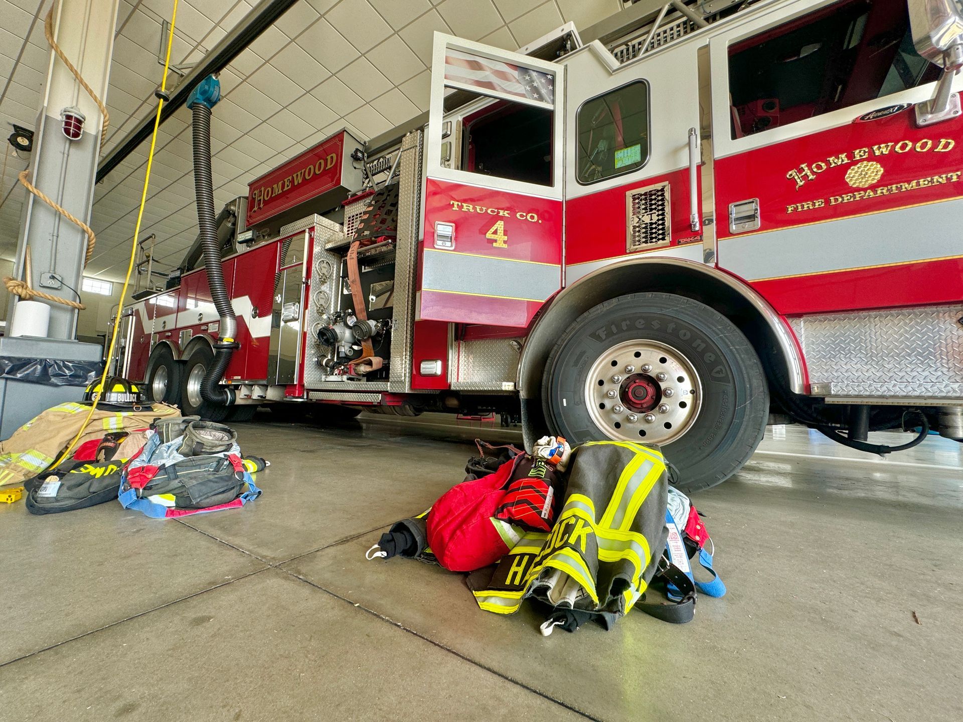 A fire truck is parked in a garage with its doors open.