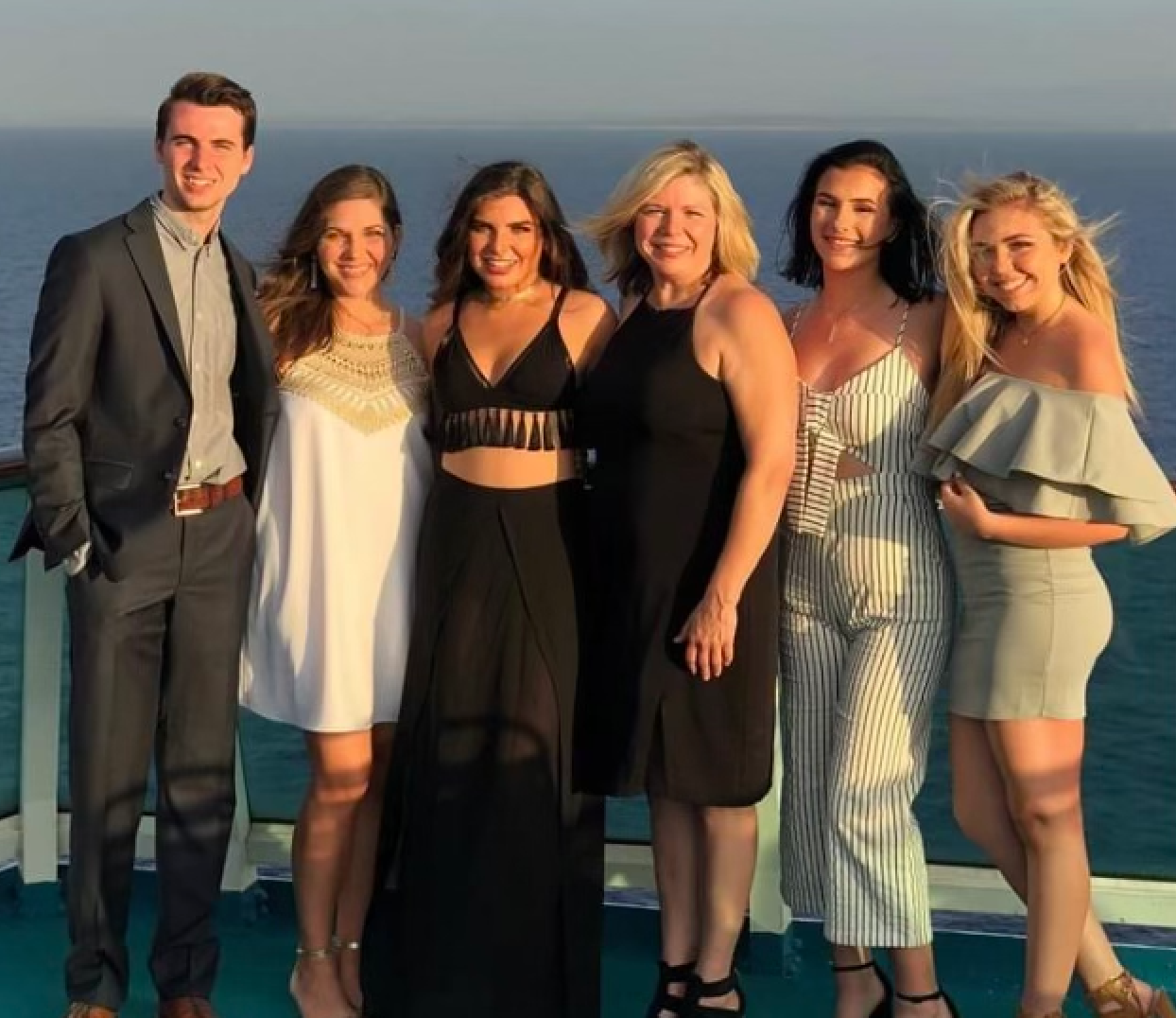 A group of people posing for a picture with the ocean in the background
