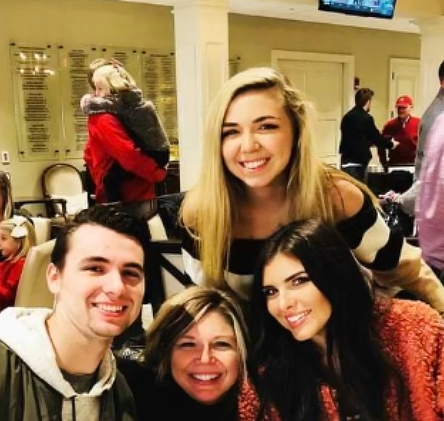 A group of people posing for a picture with a baby in the background