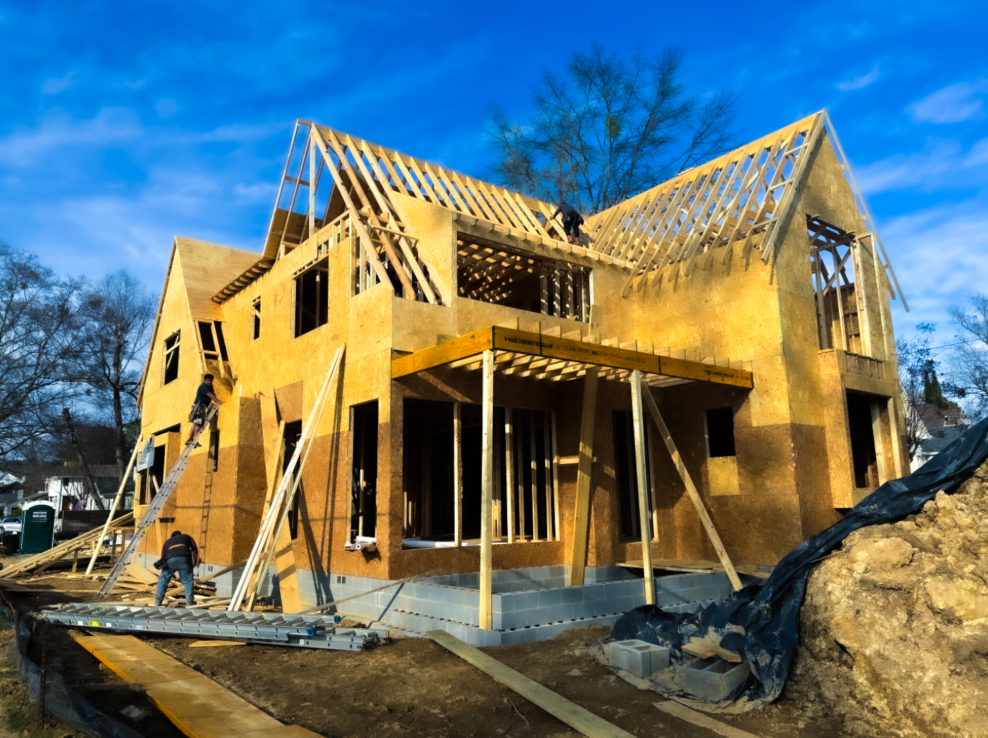 A large wooden house is being built with a blue sky in the background.