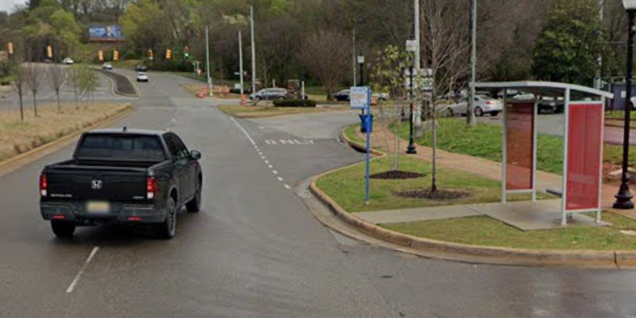 A truck is driving down a street next to a bus stop.