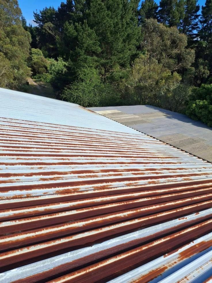A Rusty Metal Roof With Trees In The Background — Roofworx Group In Bathurst, NSW
