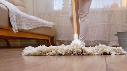 A person is mopping the floor in a living room.