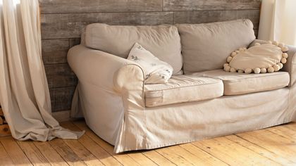 A white couch is sitting on a wooden floor in a living room.