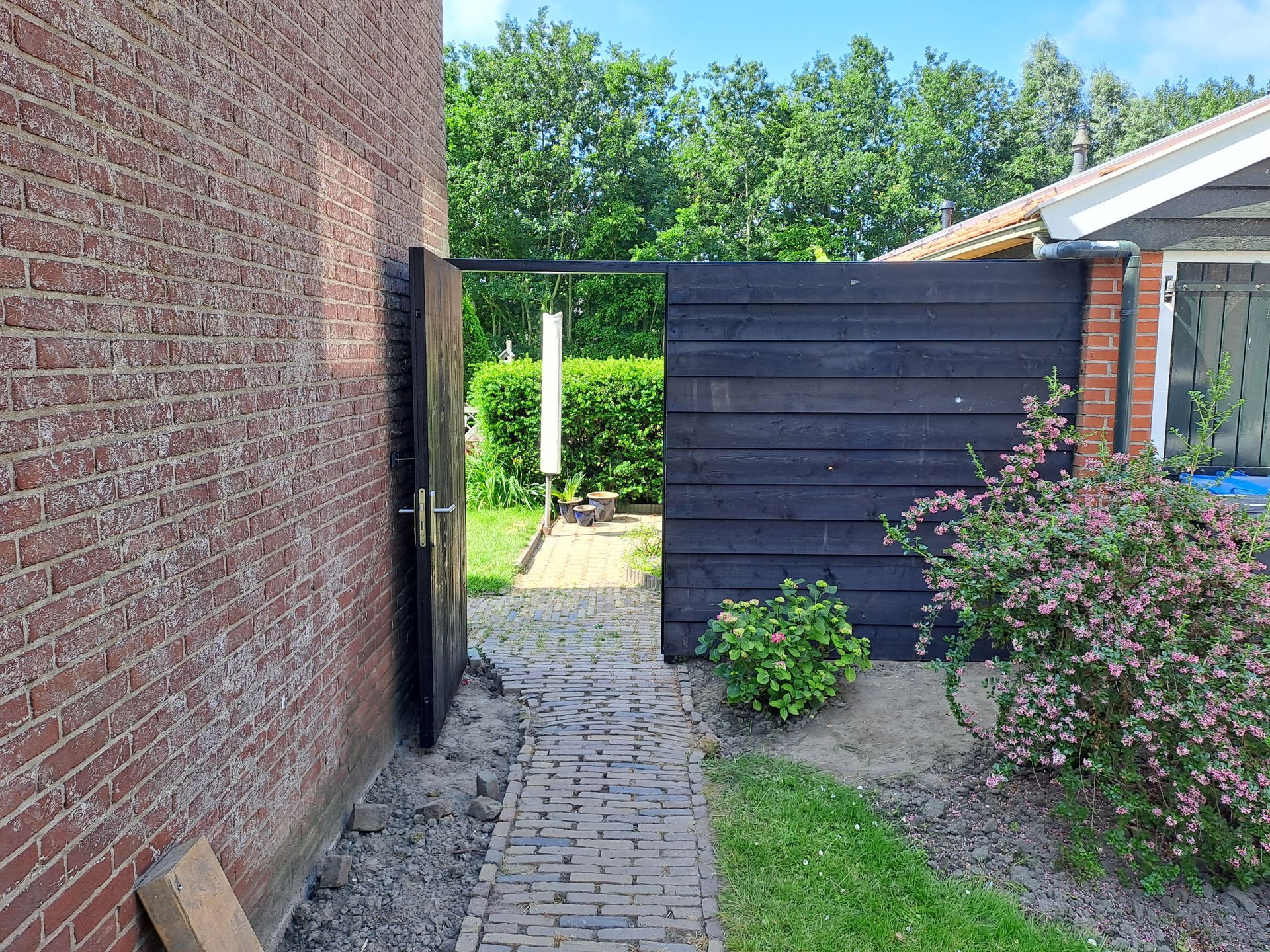 Een bakstenen muur met een zwart houten hek ervoor.