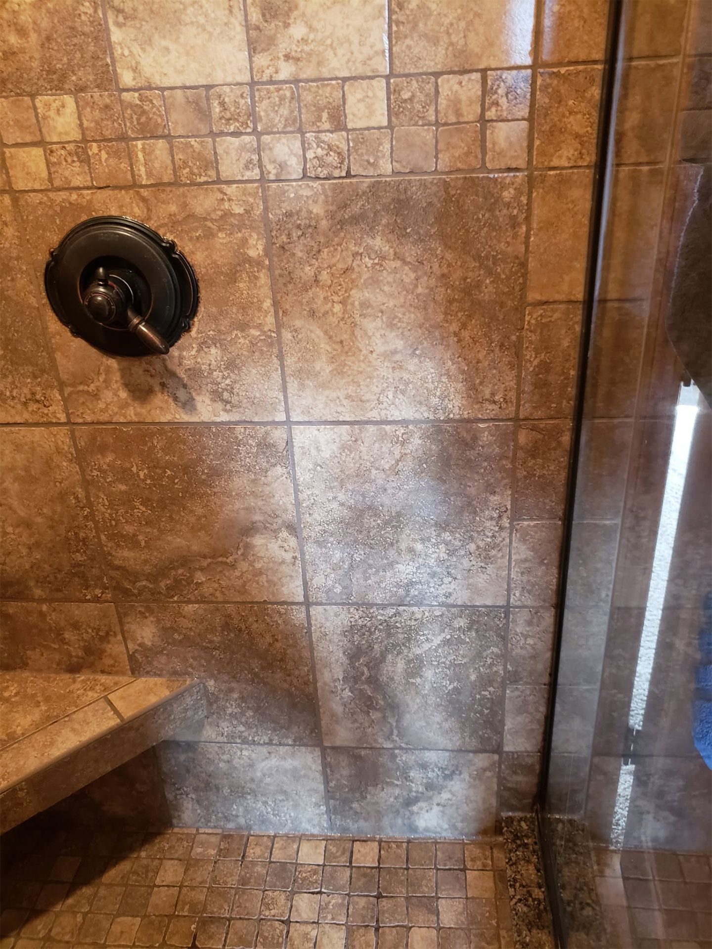 Stone-tiled shower with wall-mounted showerhead and bench seat