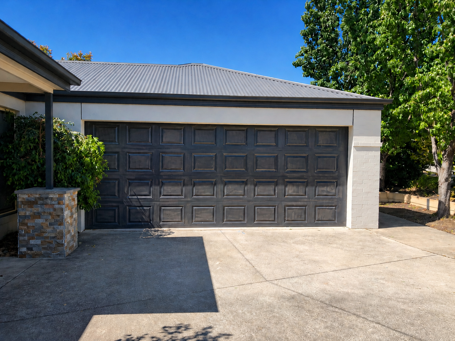 Suburban house with a two-car garage and driveway under a clear blue sky — Recoat Painting In West Wodonga, VIC