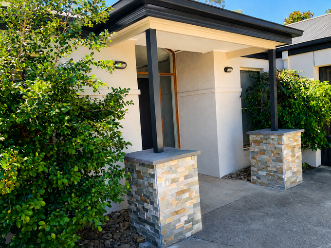 Modern house entrance with stone pillars, a white front door, and greenery along the walkway — Recoat Painting In West Wodonga, VIC