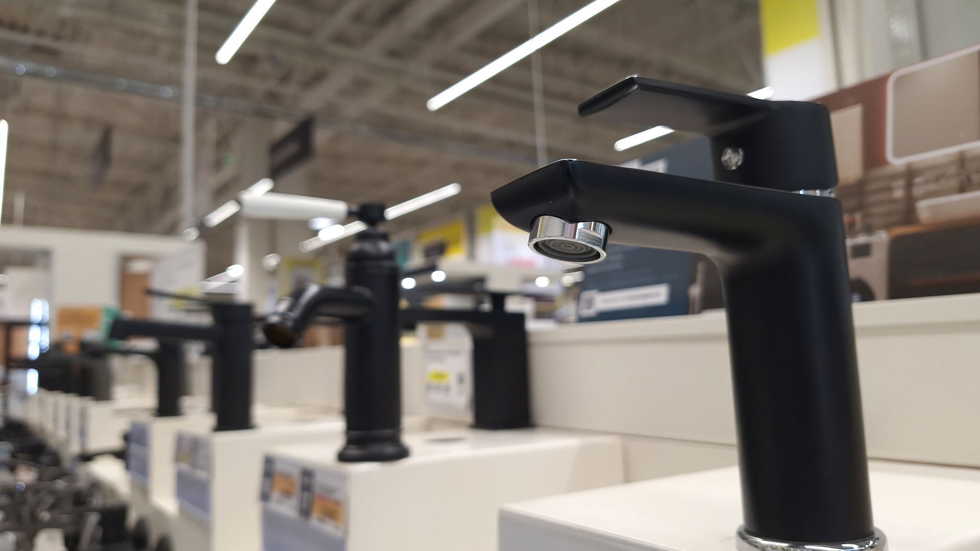 Row of black faucets on display in a store.
