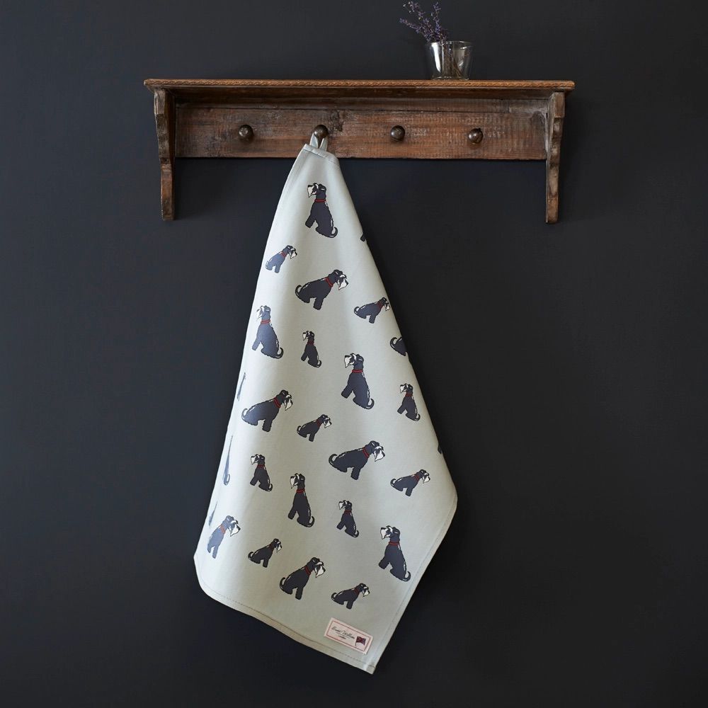Handdoek met hondenmotief hangt aan een houten rek. Donkere muur op de achtergrond.