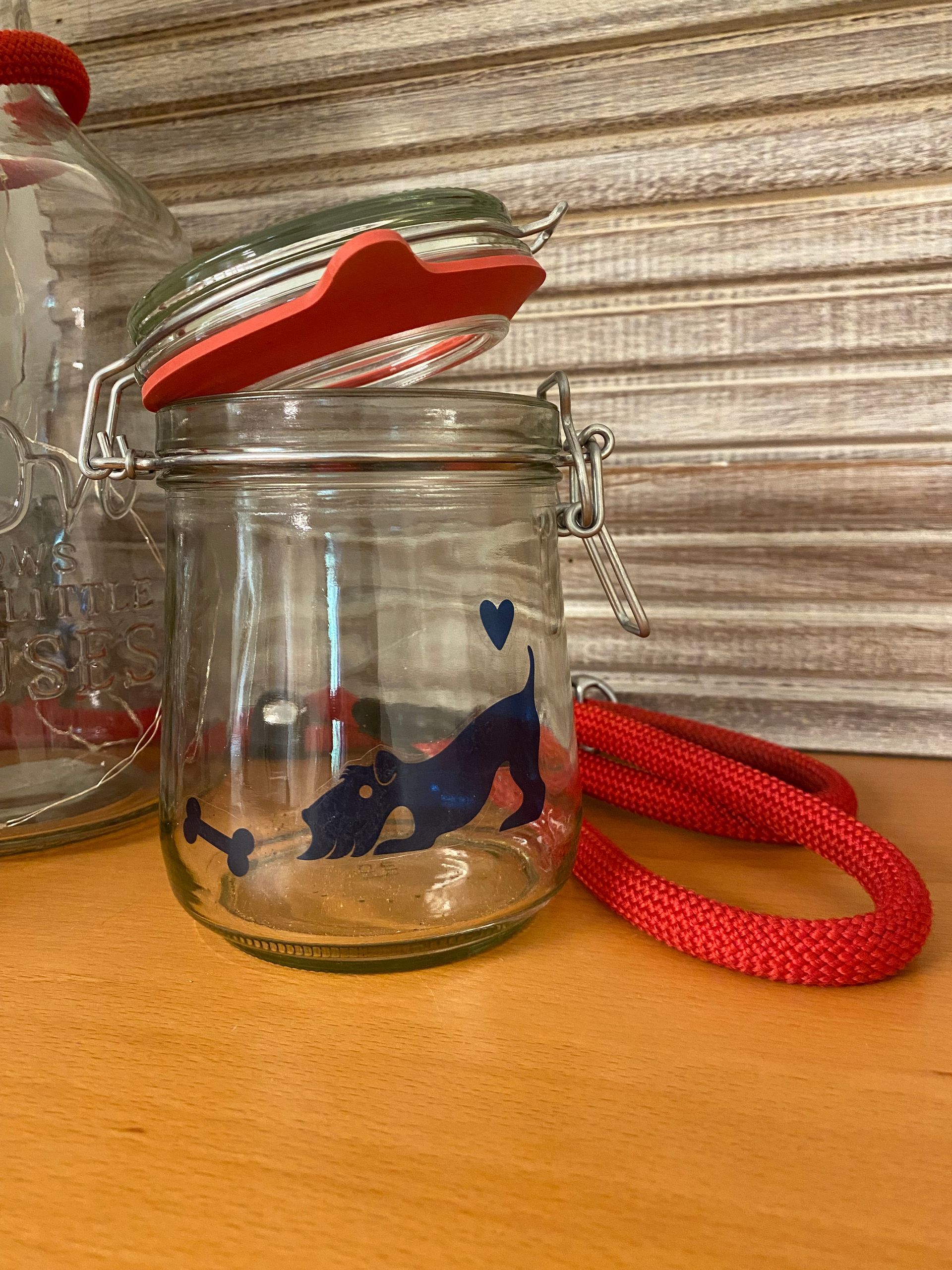 Glazen pot met rood deksel, een blauw hondensilhouet en een rood handvat.