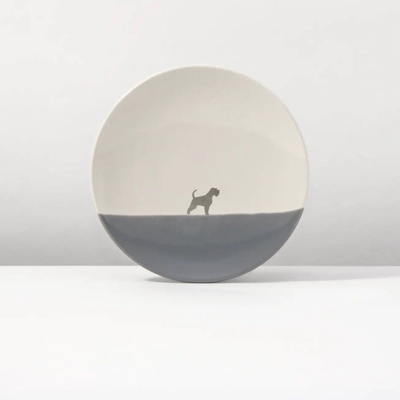 Bord met grijze onderkant, crèmekleurige bovenkant en silhouet van een hond.