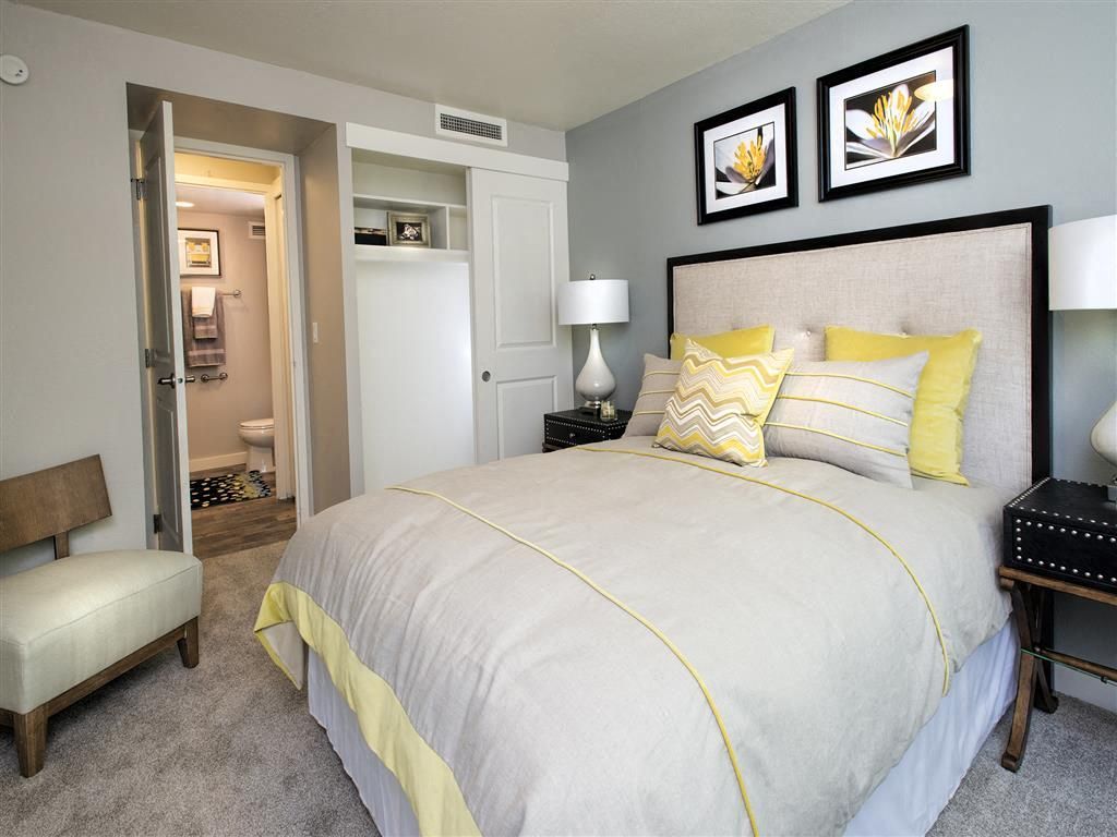 Bedroom in an apartment with a large bed, two lamps, and an open closet; bathroom visible at Harrison Tower