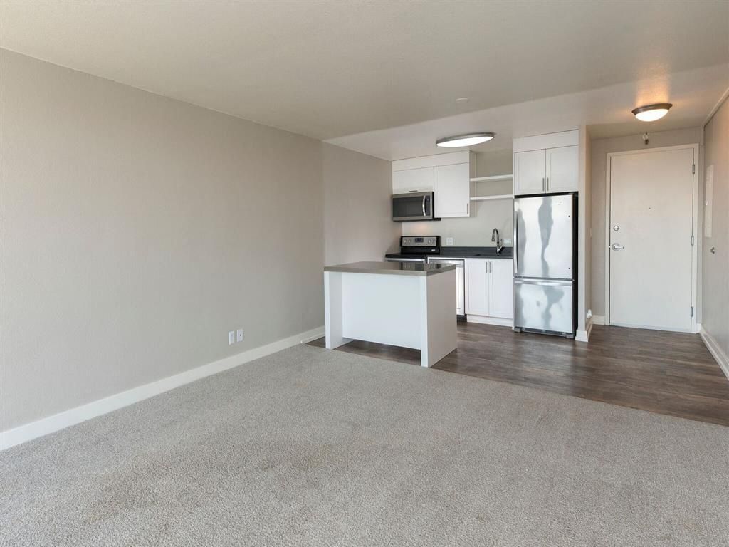 Open-plan apartment kitchen with island, white cabinets, and stainless-steel appliances at Harrison Tower