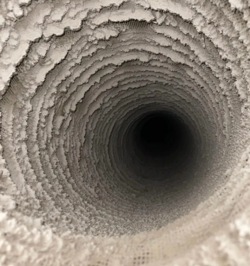Inside of a circular air duct, heavily coated with thick white debris.