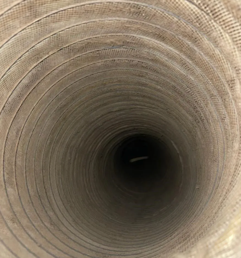 View inside a flexible air duct. The interior is light brown, fading into darkness.
