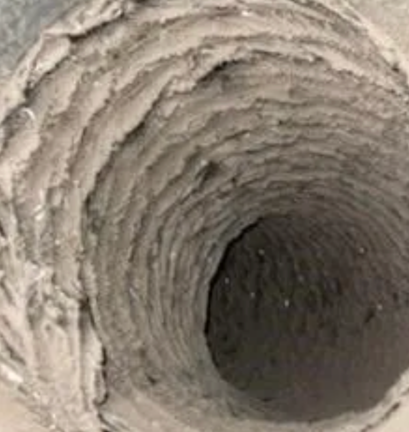 Dirty, dusty HVAC duct. The interior is covered in a thick layer of grey debris, narrowing the airflow.
