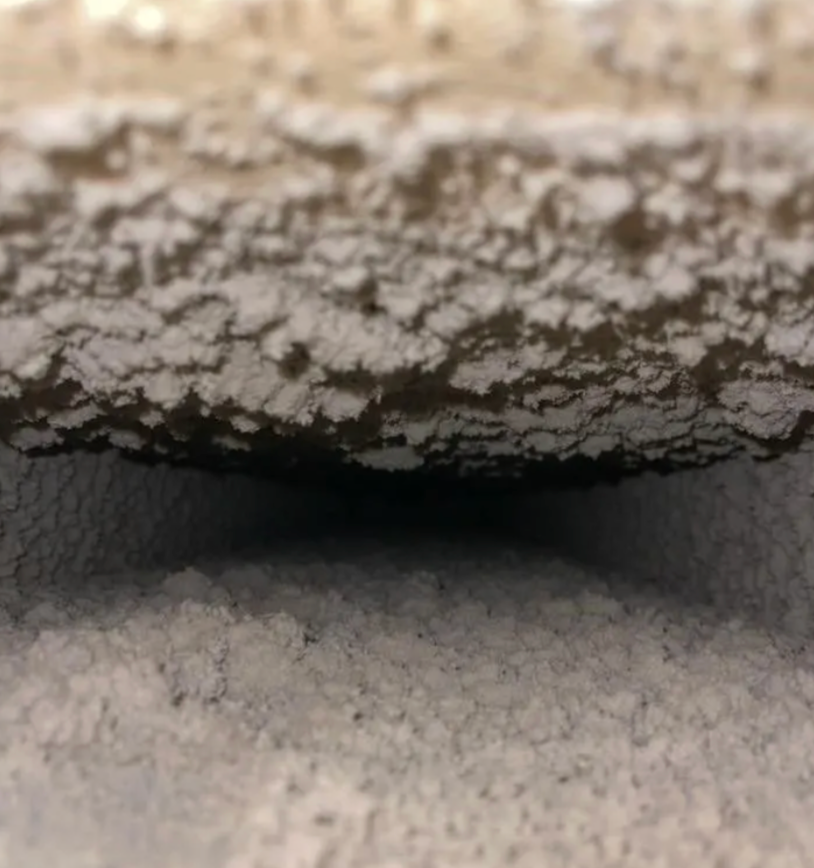 Close-up of a textured surface, possibly ceiling or underside of a structure, with a dark interior space visible.
