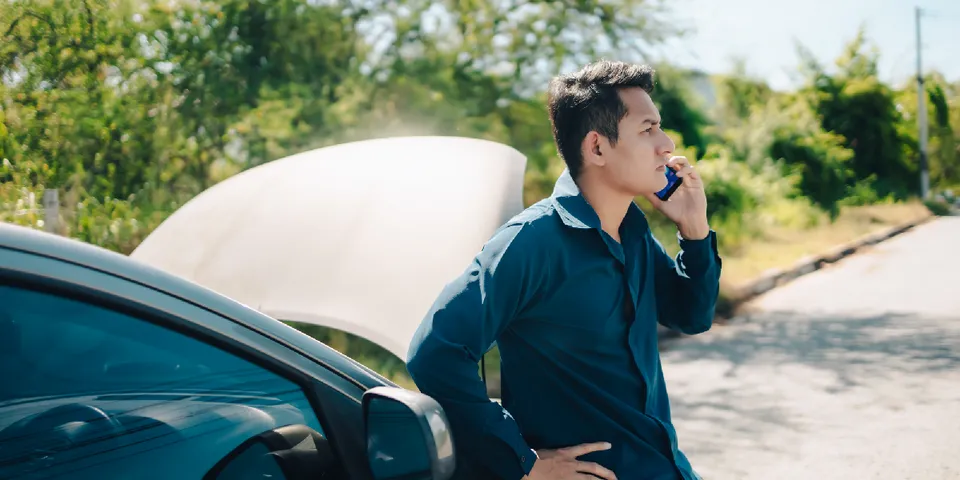 Man on phone next to car — Waipahu, HI — Westside Fender/Body & Refinishing