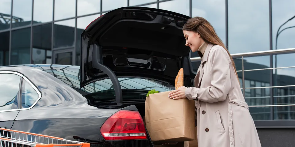 Woman putting paper bag in trunk of car — Waipahu, HI — Westside Fender/Body & Refinishing